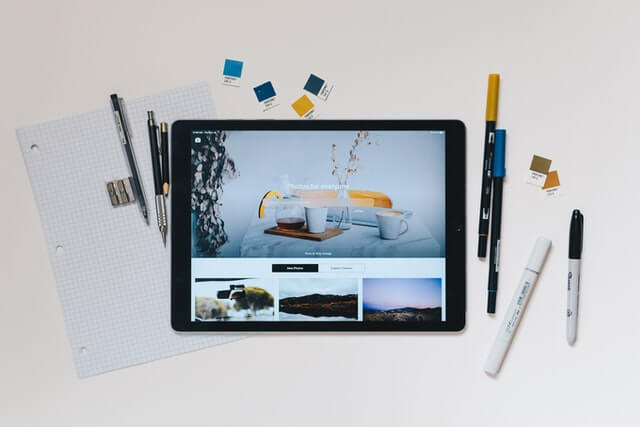 An iPad with a collection of pens, pencils, and paper.