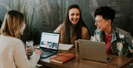 Three people laughing together at a table.