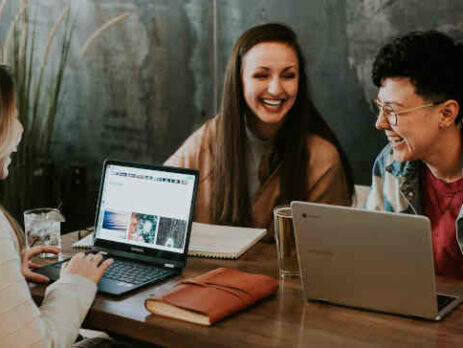 Three people laughing together at a table.