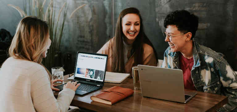 Three people laughing together at a table.