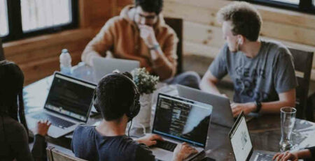 A group of coworkers working on Macbooks in an office.