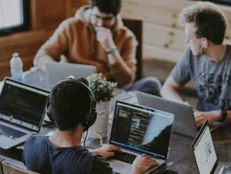 A group of coworkers working on Macbooks in an office.