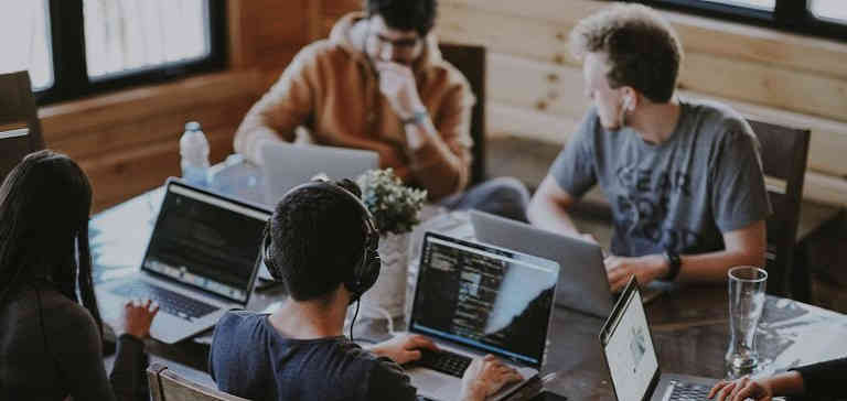 A group of coworkers working on Macbooks in an office.