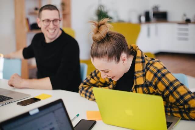 A woman and man laughing in a workspace.