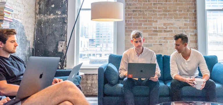 Three men sitting on couches in an office.