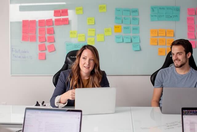 A man and woman at a desk in a conference room.