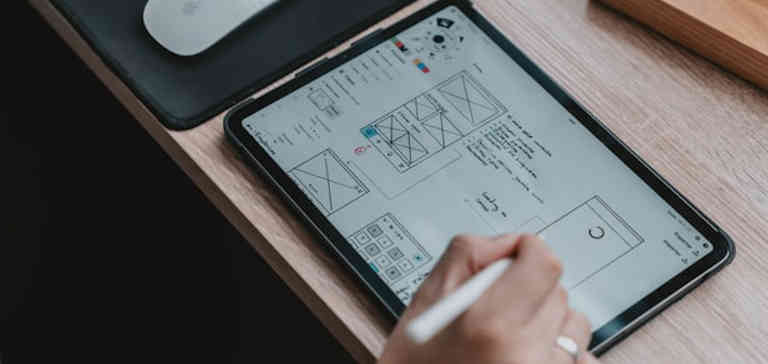Image of UI designer writing on digital pad.