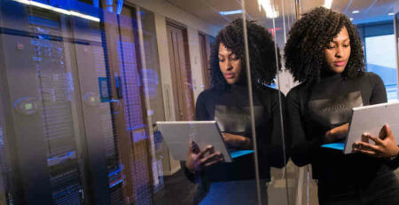 Woman with a laptop near a glass wall.