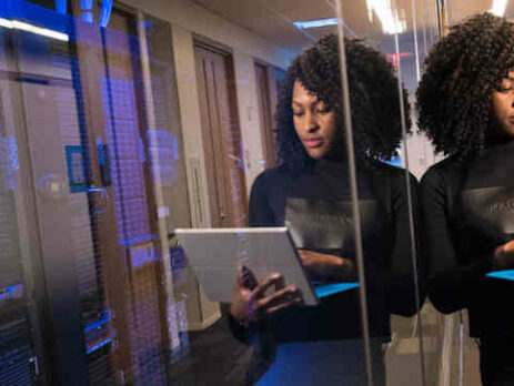 Woman with a laptop near a glass wall.