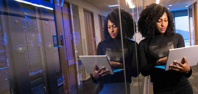 Woman with a laptop near a glass wall.