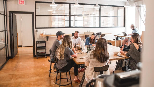 Talking people sitting beside a table.