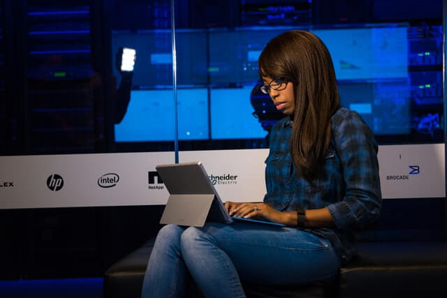 Woman in blue and black plaid using a tablet.