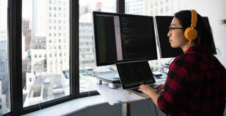 Woman working on a computer and looking out a window.