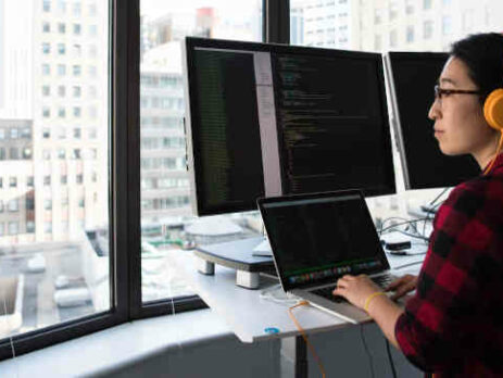 Woman working on a computer and looking out a window.