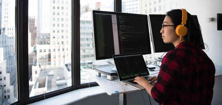 Woman working on a computer and looking out a window.