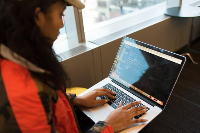 Woman in red and black using a MacBook.