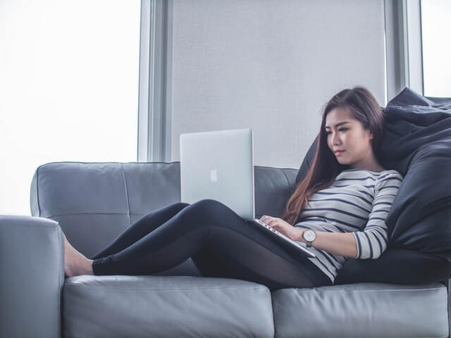  Woman using a laptop sitting on the couch.