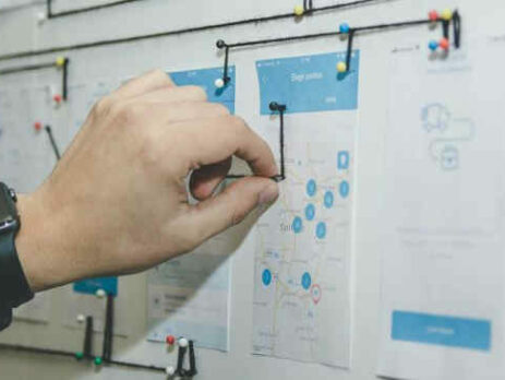 A person works with blue and white paper on a bulletin board.