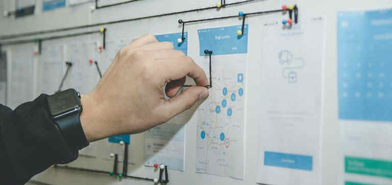 A person works with blue and white paper on a bulletin board.