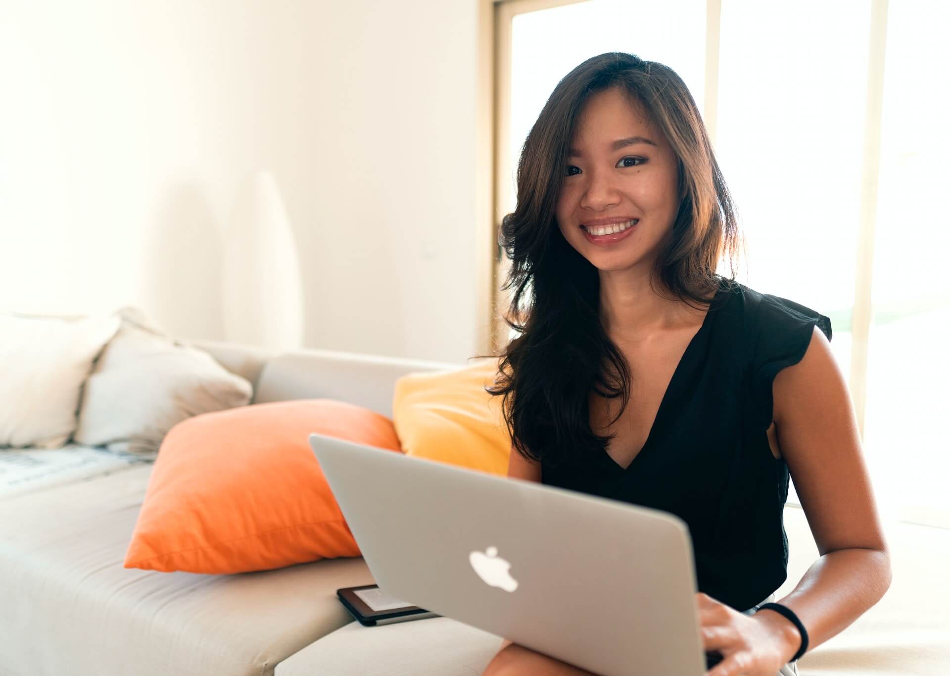 Woman in black shirt smiling with a laptop computer.