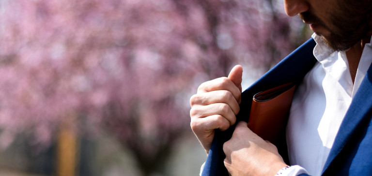 A man in a blue suit reaches for his wallet.