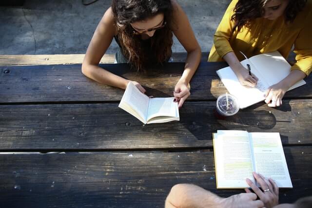 Three people at a table with books.