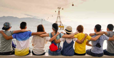 A group holding shoulders and sitting on a wall.