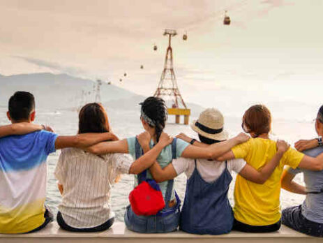 A group holding shoulders and sitting on a wall.