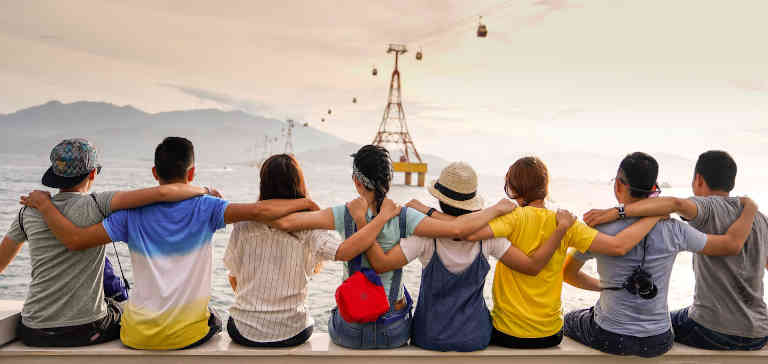 A group holding shoulders and sitting on a wall.