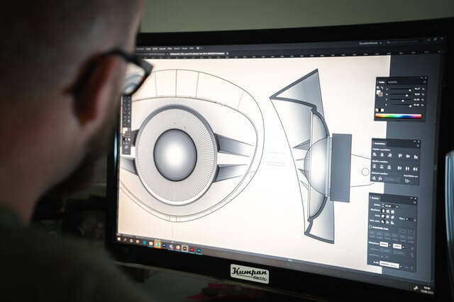 A man looking at a black flatscreen computer monitor.