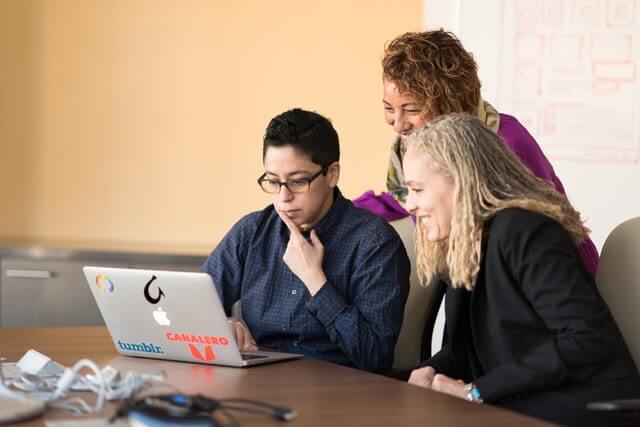 Three people have a meeting with a laptop.