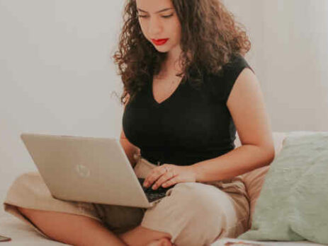 A woman in a black shirt works on a laptop.