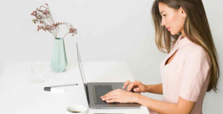 A girl in a pink dress typing on the computer.