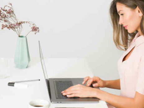 A girl in a pink dress typing on the computer.