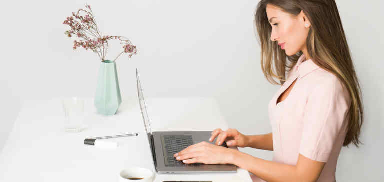 A girl in a pink dress typing on the computer.