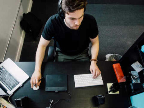 A man sitting at a desktop computer working.