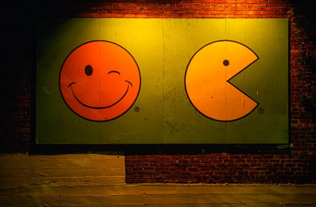 A red and yellow smiley face are painted against a green background.