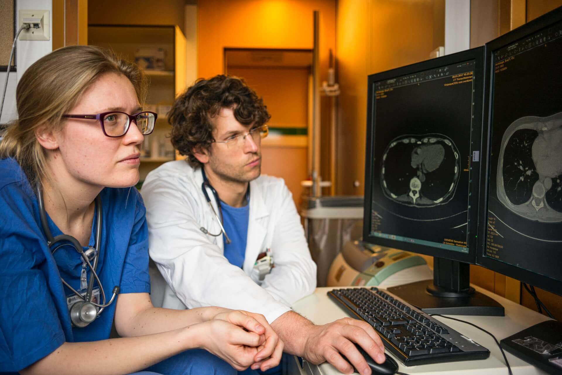 Two doctors look at MRI results on a computer screen.