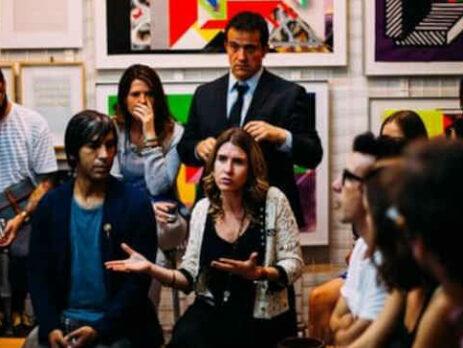 A woman speaks before a crowd of businesspeople.