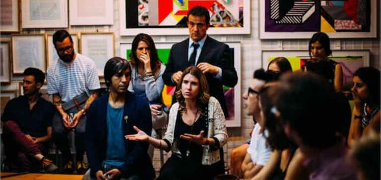 A woman speaks before a crowd of businesspeople.