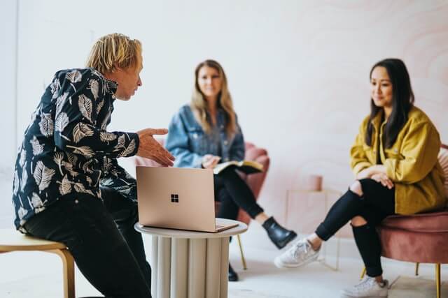 A man and two women discuss ideas during a business meeting.