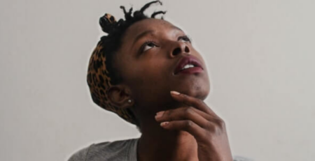 A woman in a gray shirt looks up as she is thinking.