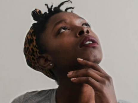 A woman in a gray shirt looks up as she is thinking.