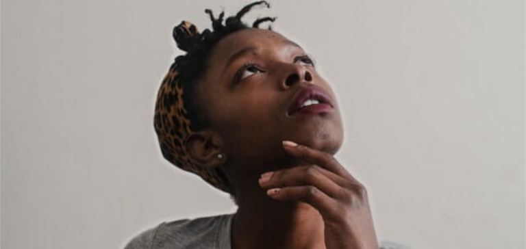 A woman in a gray shirt looks up as she is thinking.