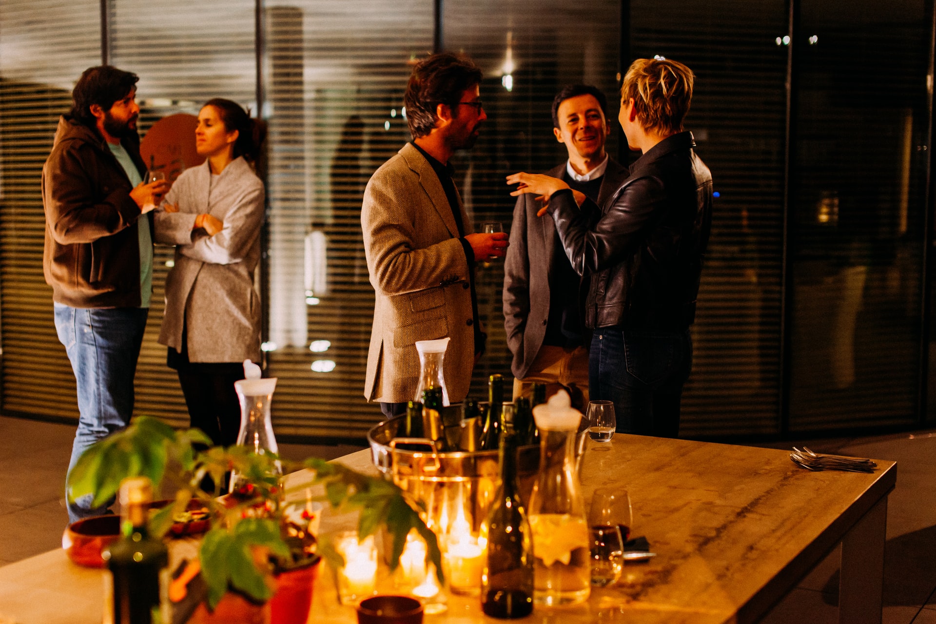 Five people stand and talk to one another at a party.