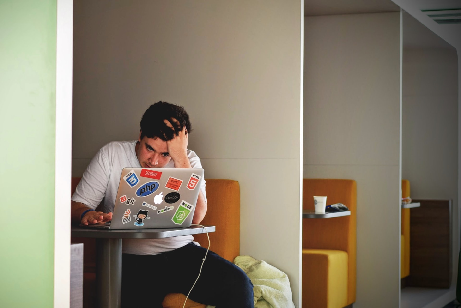 A man in a white shirt works on a MacBook.