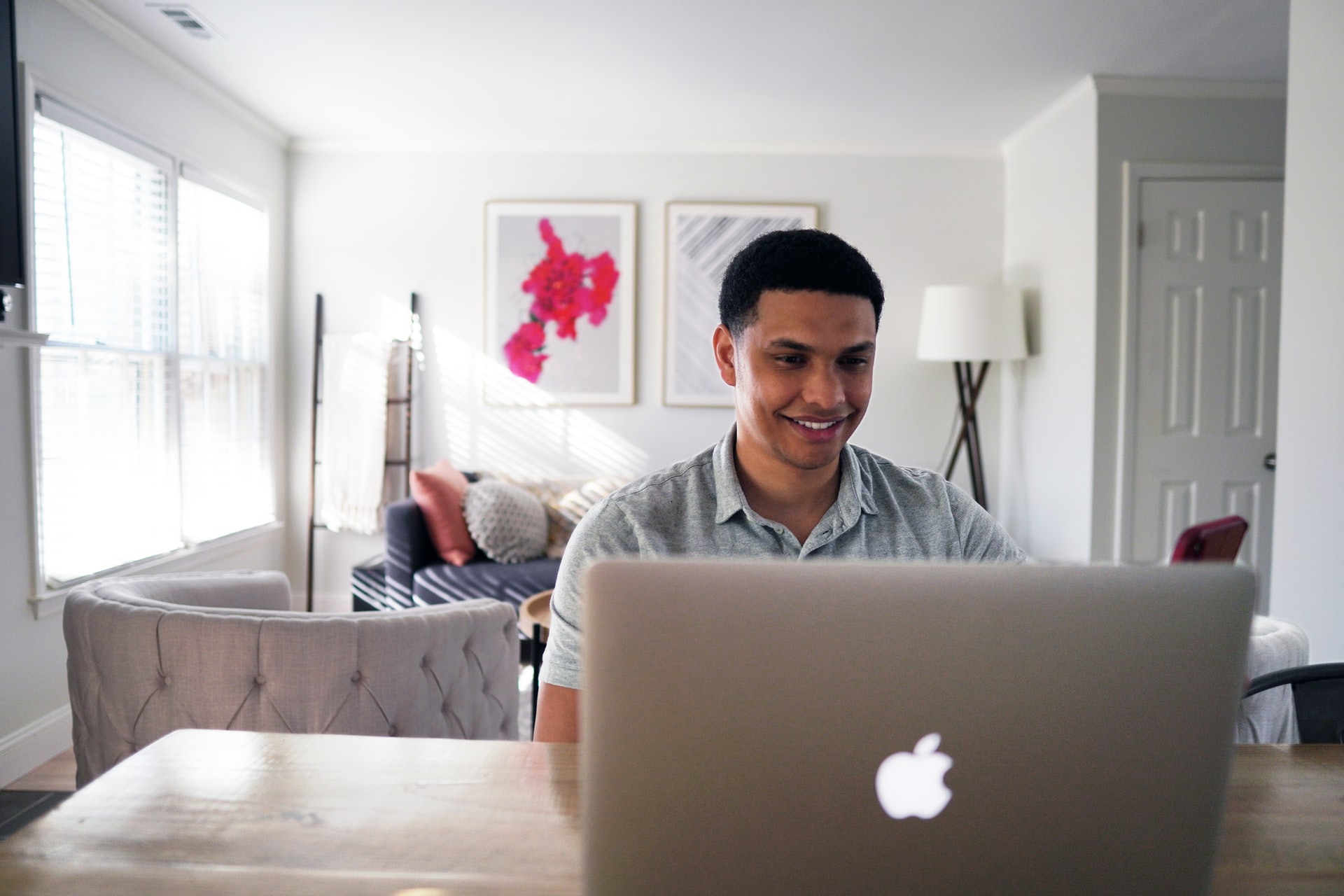 A man in a grey collared shirt works on a laptop.