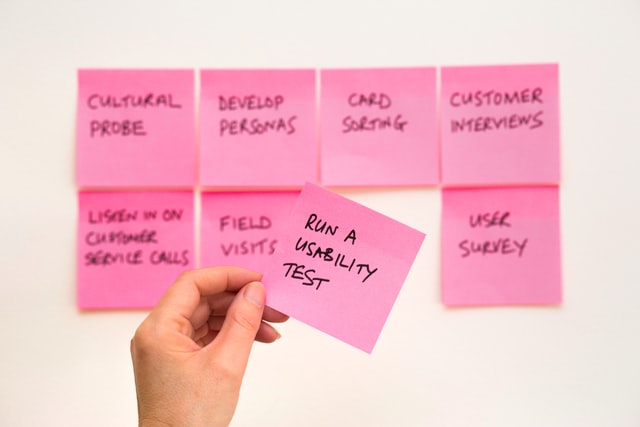 A person holding a pink sticky note.