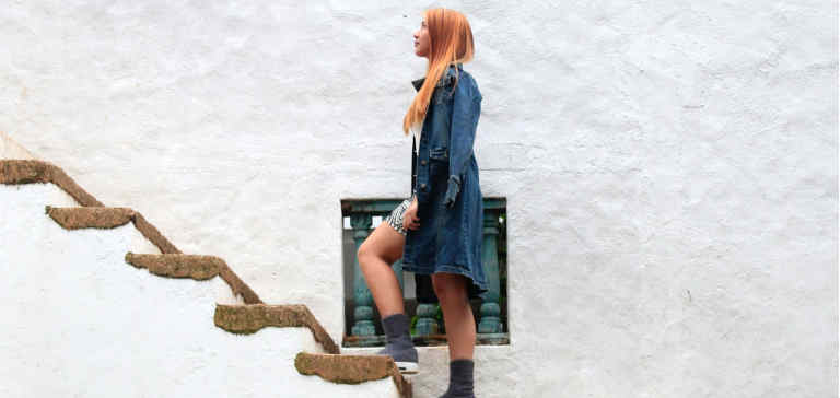 A redheaded woman climbs a staircase.