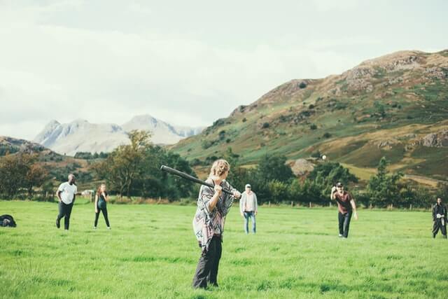 People play baseball in a field of green grass.